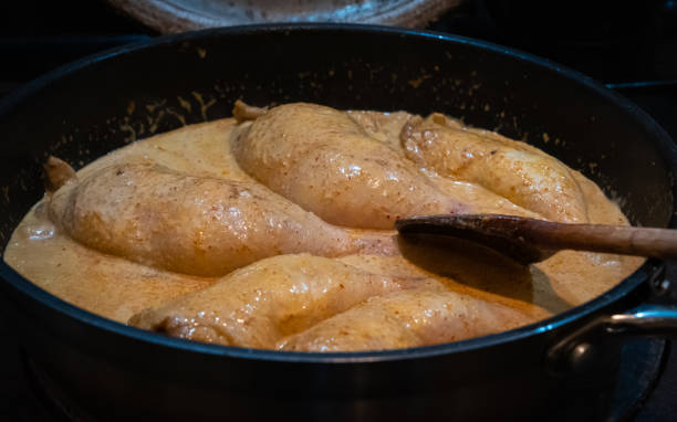 Red thai chicken curry simmering in a pan on a stove stock photo