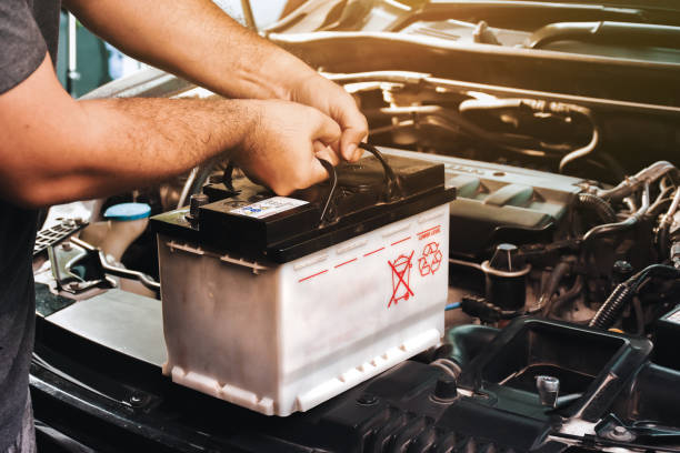 자동차 정비사는 자동차 전기 유지 보수를위한 교체 자동차 배터리를 운반합니다. - battery replacement 뉴스 사진 이미지