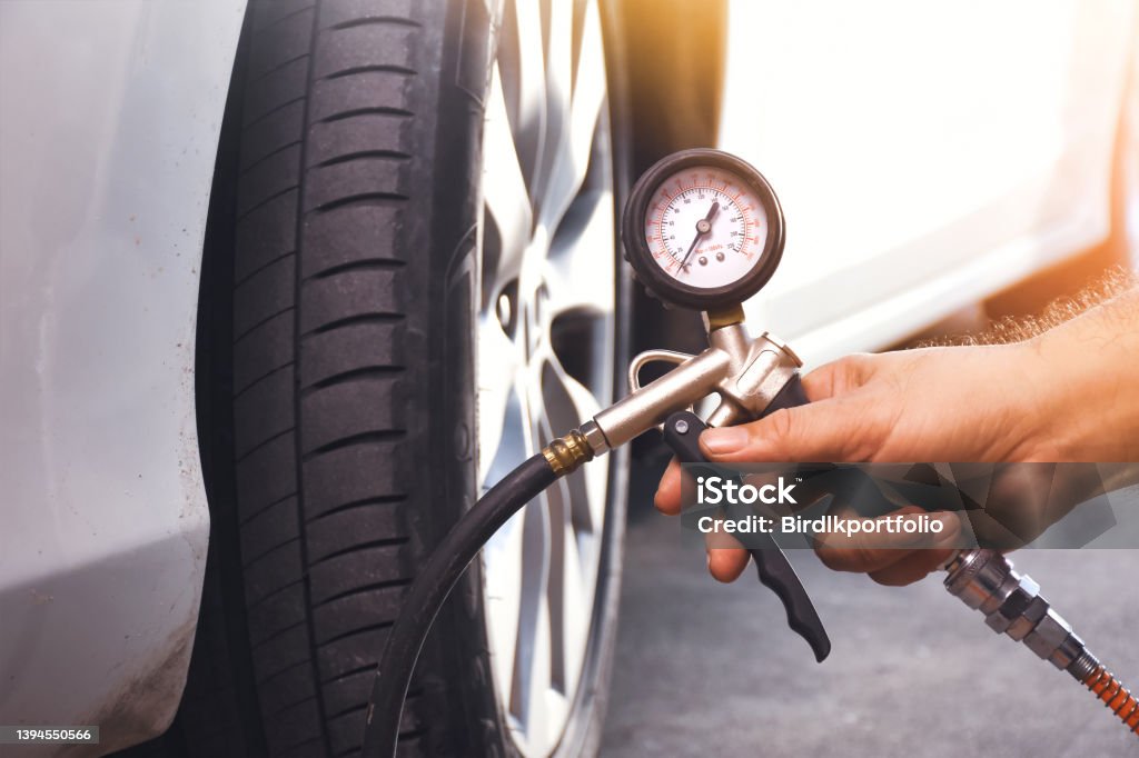 A auto mechanic inflates a tire with an air tire inflating gun A auto mechanic inflates a tire with an air tire inflating gun in the auto repair garage Tire - Vehicle Part Stock Photo
