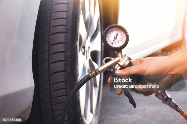 A Auto Mechanic Inflates A Tire With An Air Tire Inflating Gun Stock Photo - Download Image Now