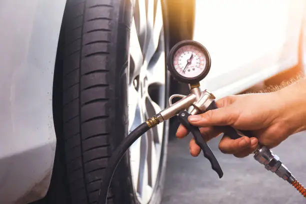 Photo of A auto mechanic inflates a tire with an air tire inflating gun