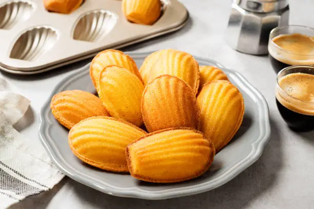 Perfect French madeleine cookies, buttery and delicate, served with cup of coffee. Light gray background.