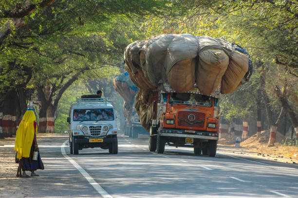 Rajasthan, India - March 05, 2006: Cars with passengers and overloaded trucks circulating on a rural road in the region