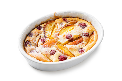 Traditional french pie clafoutis with fresh summer peaches and raspberry. isolated on white background