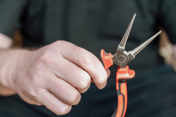 istock The hand of a mature man holding round pliers. Hand-held locksmith tool with smooth surface finish and diameter tapering toward the tips. 1394553381