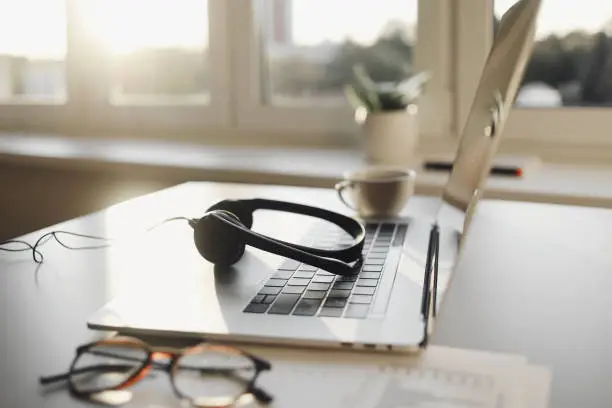 Photo of Work place in office, headset, laptop computer, glasses at office desk