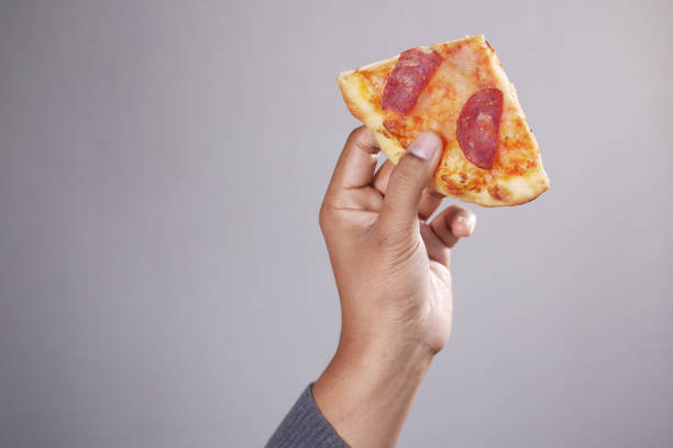 istock man hand picking slice of pizza against white background 1394554614