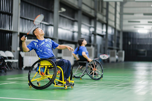 Handicapped badminton players actively training their skills in indoor badminton court