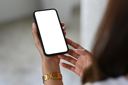 Las manos se cierran con una mujer joven usando un teléfono inteligente con pantalla táctil con pantalla blanca en blanco. para la tecnología y el concepto de negocio. photo