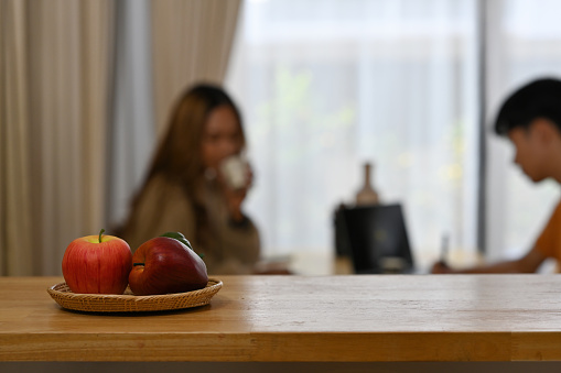 Cropped view object focused.  two apples on a counter top as a foreground and a couple sitting behind as a background. for home and food concept.