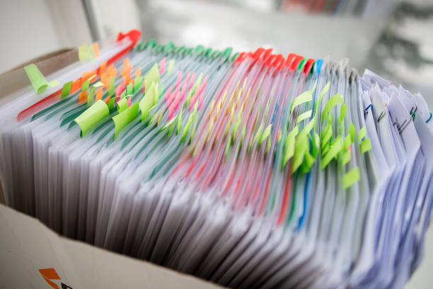 istock Stack of business report paper file on modern white office desk with bokeh background. 1394557314