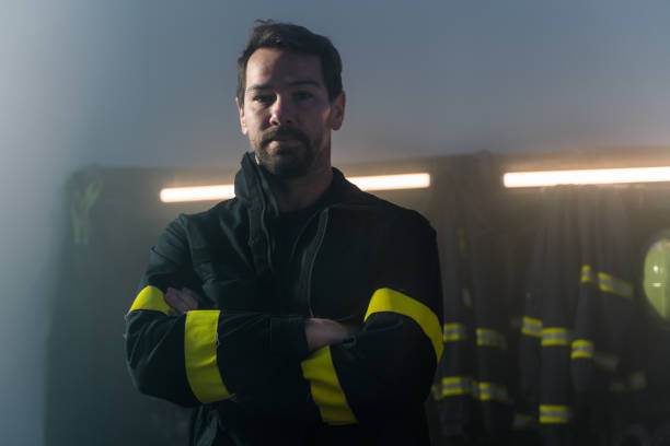 istock Mature firefighter in fire station at night, looking at camera. 1394563253