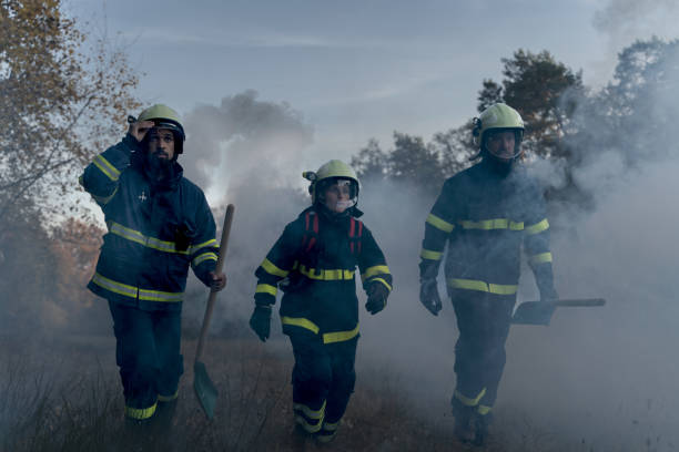 istock Firefighters men at action, running through smoke with shovels to stop fire in forest. 1394563532