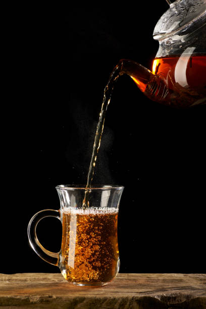 istock Hot tea pours into a transparent mug on a black background 1394567043