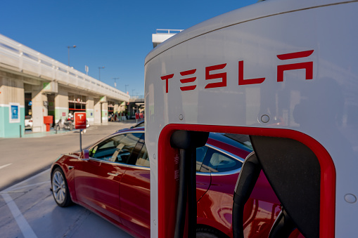 Murcia, Spain - February 2, 2021: A red Tesla Model 3 is parked in a Supercharger station in a mall of Murcia, Spain. This station has 10 Superchargers, available always and up to 150 kW