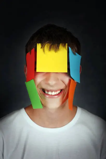 Portrait of Teenager on the dark background with Colored Paper on a Face
