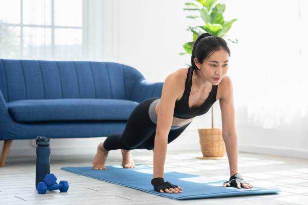 istock Asian girl doing push ups workout exercise on exercise mats concentration on shoulder muscle at home.Athletic female pushing up training with cardio exercise in living room.Self workout concept 1394575403
