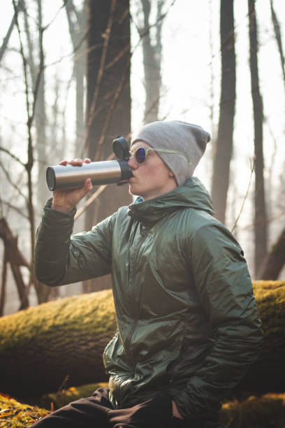 istock experienced hiker sitting on a tree trunk in the wilderness, drinking his hot tea from a thermos during a break in the walk. Real people discovering the biodiversity of European forests. Real smile 1394578355