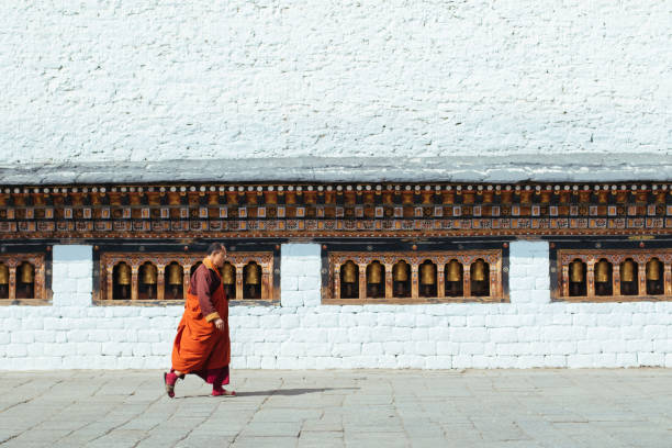 thimphu, bhoutan-25 février 2018: un moine du bhoutan marchant devant les moulins à prières - prayer wheel photos et images de collection