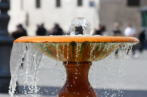 water spilling from a water fountain in Rome, Italy with blurred people in the background