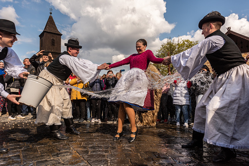 HOLLOKO, HUNGARY - April 18, 2022: Easter festival in the folklore village of Holloko in Hungary. Guys sprinkle water on girls according to tradition.