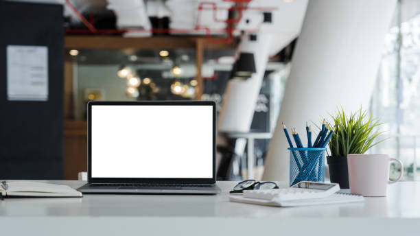 istock Mockup laptop computer with white screen put on desk table of business office. 1394604003