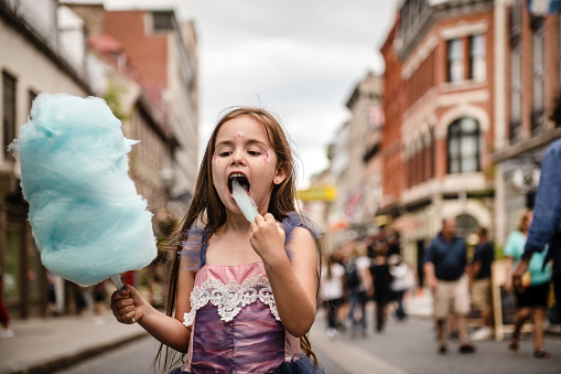 5 years little girl eating a cotton candy in the city, quebec, canada