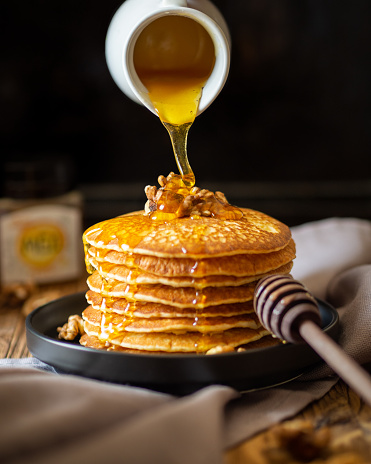 Honey is poured on a stack of pancakes