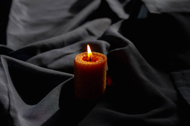 istock A large wax candle with a honeycomb texture on a dark blue fabric burns with a flame 1394623975
