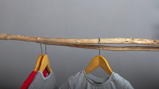 Ecological concept in the production and storage of clothing, T-shirts made of natural cotton on wooden hangers on a gray background.