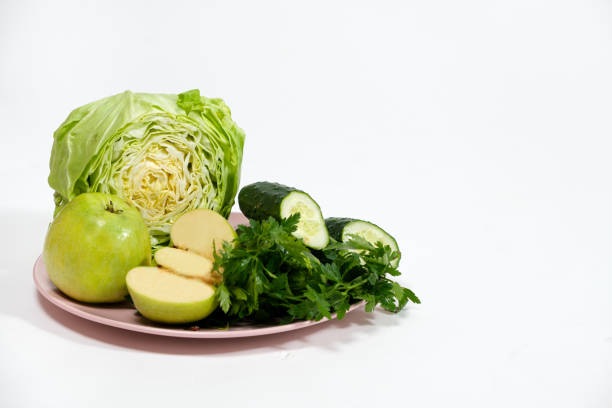 une assiette avec des légumes verts et des fruits - chou, pommes, concombres et persil sur fond blanc avec une place pour le texte - chlorophyll photos et images de collection