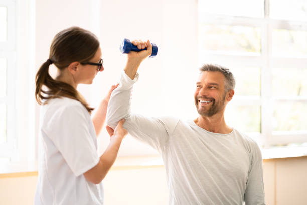 Physical Rehabilitation Therapist Helping Man Physical Rehabilitation Therapist Helping Man. Physiotherapy Rehabilitation physical therapy stock pictures, royalty-free photos & images