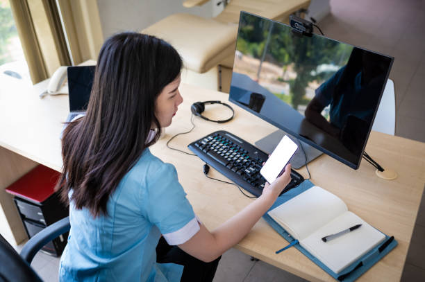 istock Female Asian medical worker using smart phone while working at her office desk 1394631066