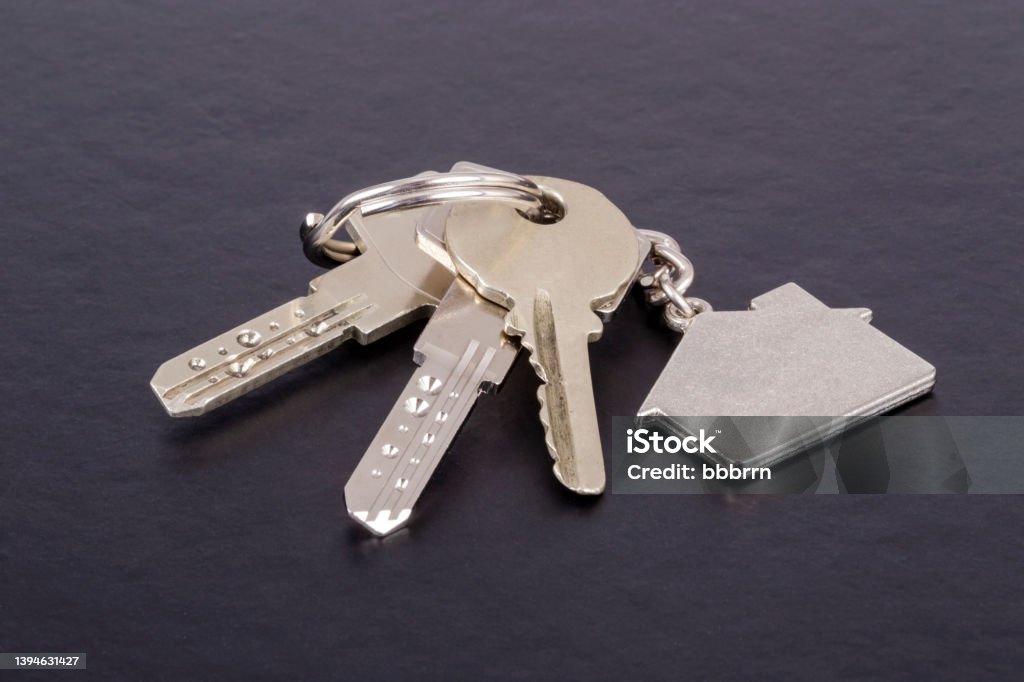 keys with house shaped keyring on black keys with house shaped keyring on black with copy space House Key Stock Photo