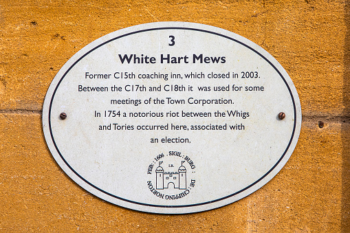 Chipping Norton, UK - April 10th 2022: Plaque marking the location and history of White Hart Mews in the historic town of Chipping Norton, in Oxfordshire, UK.