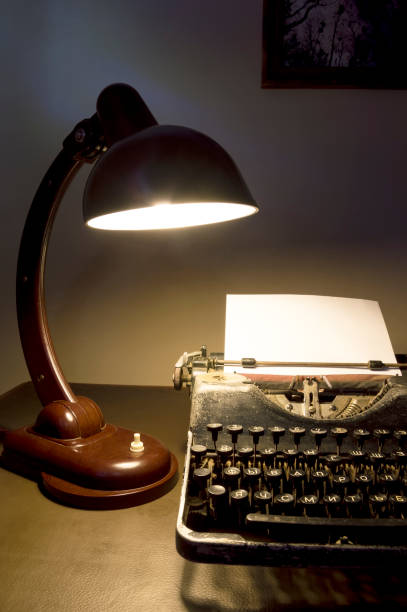 istock Vintage typewriter with a desk lamp on at night. 1394634894