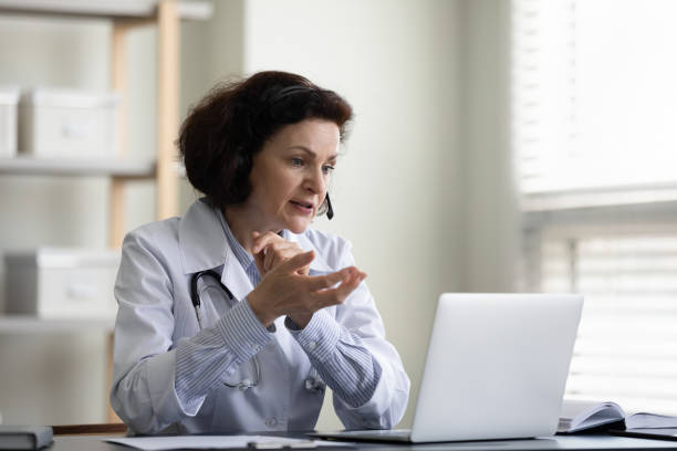 istock Serious female mid adult doctor using laptop computer at workplace 1394637395