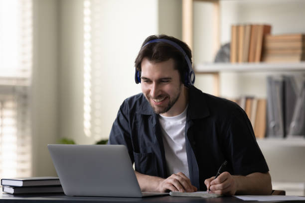istock Happy millennial student guy in headphones watching learning virtual webinar 1394637411