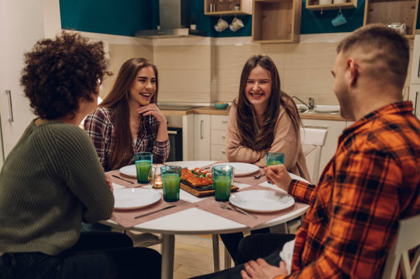 istock Group of friends enjoying dinner while sitting at the kitchen table together 1394639679