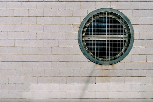 White brick facade with a circular metal window. Copy space