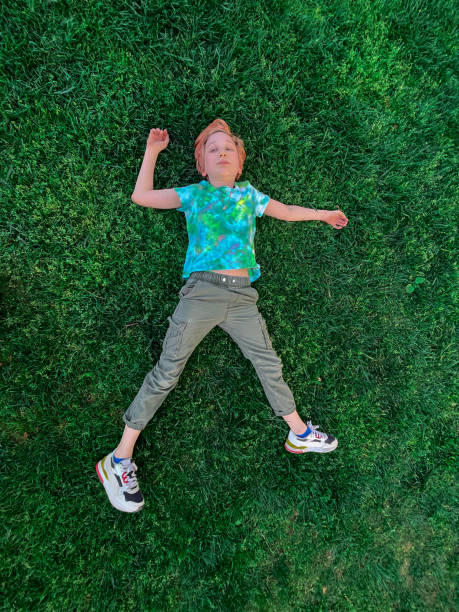 istock Cute funny boy lying on green grass in park 1394642692