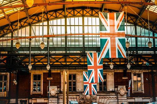 Looking east from Charing Cross, rows of British flag bunting strung between buildings on major thoroughfare linking Westminster and London.