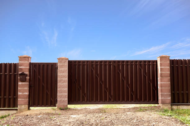 istock Brown metal profile fence with block posts. Entry group: gate, wicket and postbox. Opaque surface, vertical lines. Security. Private property fencing. Exterior. Pavement tiles on parking. Isolated 1394647108