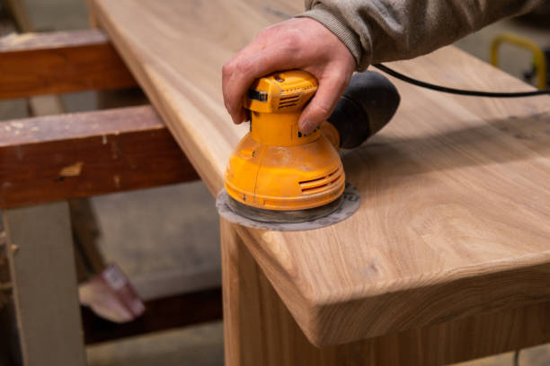istock Closeup of carpenter sanding wood table with orbital sander in a workshop 1394647207