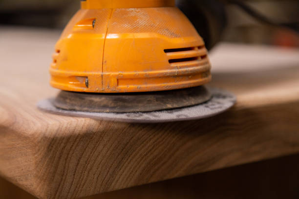 istock Closeup of carpenter sanding wood table with orbital sander in a workshop 1394648243