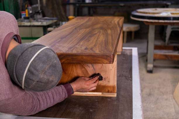 istock Carpenter coating a wooden table with protective flaxseed oil 1394649119
