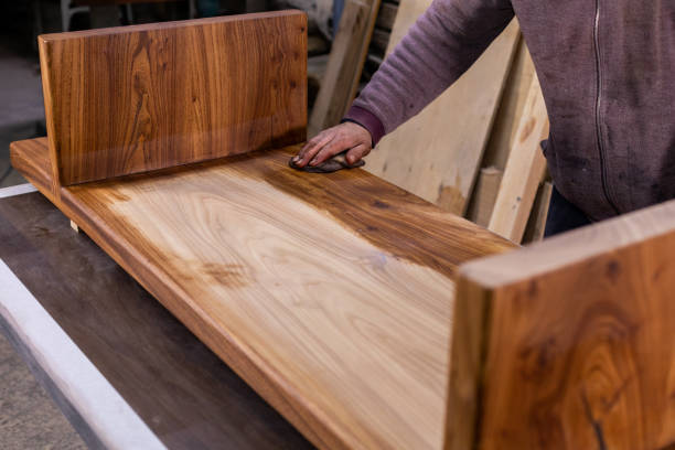 istock Carpenter coating a wooden table with protective flaxseed oil 1394649429
