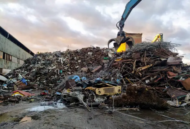 Photo of Old rusty metal. The hydraulic crane is used to collect scrap metal at the disposal site