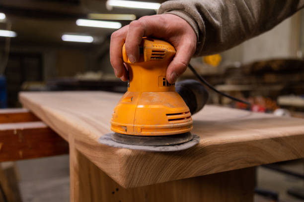 istock Closeup of carpenter sanding wood table with orbital sander in a workshop 1394650262