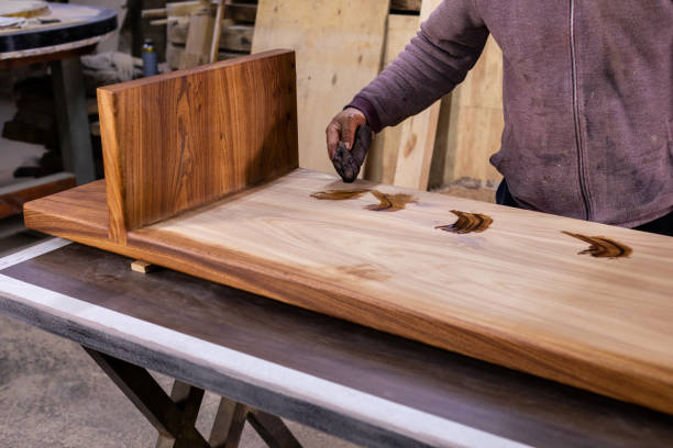 istock Carpenter coating a wooden table with protective flaxseed oil 1394650466